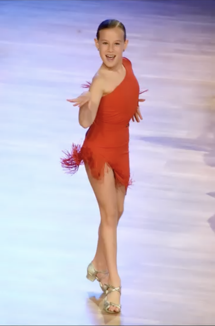 Competición de baile con una chica rubia bailando en solitario, luciendo un elegante vestido rojo. Momentos de técnica y pasión en una competición de baile en Top Center Barcelona. Ideal para destacar en búsquedas relacionadas con competiciones de baile, trajes de baile y estilos de danza individual.